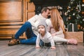 Family holiday New Year and Christmas. Young caucasian family mom dad son 1 year sit wooden floor near fireplace christmas tree on Royalty Free Stock Photo