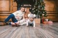 Family holiday New Year and Christmas. Young caucasian family mom dad son 1 year sit wooden floor near fireplace christmas tree on Royalty Free Stock Photo