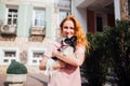 The theme is the friendship of man and animal. Beautiful young red hair Caucasian woman holding a pet dog Chihuahua breed near a Royalty Free Stock Photo