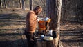 Theme hiking and travel. A Caucasian tourist man unpacks an orange backpack, takes out his things and puts them on a stump in the