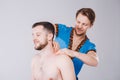 Theme massage and body care. A handsome Caucasian male doctor in blue uniform and beard diagnosing muscles of neck and shoulders,