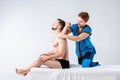 Theme massage and body care. A handsome Caucasian male doctor in blue uniform and beard diagnosing muscles of neck and shoulders,
