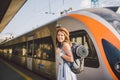 Theme railway and travel. Portrait young caucasian woman with toothy smile standing at train station train background with backpac Royalty Free Stock Photo