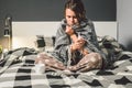 The theme is seasonal cold, runny nose flu virus infection. Young Caucasian woman at home bedroom bed sitting wrapping blanket, Royalty Free Stock Photo