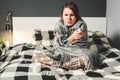 The theme is seasonal cold, runny nose flu virus infection. Young Caucasian woman at home bedroom bed sitting wrapping blanket, Royalty Free Stock Photo