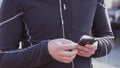 Theme sport and health. A young Caucasian man uses a smartphone smarfton to listen to music on headphones. Technology