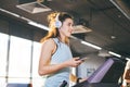 Theme sport and music. A beautiful Caucasian woman running in gym on treadmill. On head big white headphones, the girl listens to Royalty Free Stock Photo