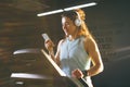Theme sport and music. A beautiful Caucasian woman running in gym on treadmill. On head big white headphones, the girl listens to Royalty Free Stock Photo