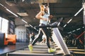 Theme is sport and music. A beautiful inflated woman runs in the gym on a treadmill. On her head are big white headphones, the gir Royalty Free Stock Photo