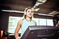 Theme is sport and music. A beautiful inflated woman runs in the gym on a treadmill. On her head are big white headphones, the gir Royalty Free Stock Photo