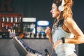 Theme is sport and music. A beautiful inflated woman runs in the gym on a treadmill. On her head are big white headphones, the gir Royalty Free Stock Photo