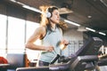 Theme is sport and music. A beautiful inflated woman runs in the gym on a treadmill. On her head are big white headphones, the gir Royalty Free Stock Photo