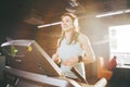 Theme is sport and music. A beautiful inflated woman runs in the gym on a treadmill. On her head are big white headphones, the gir Royalty Free Stock Photo