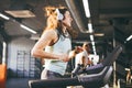 Theme is sport and music. A beautiful inflated woman runs in the gym on a treadmill. On her head are big white headphones, the gir Royalty Free Stock Photo