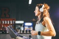 Theme is sport and music. A beautiful inflated woman runs in the gym on a treadmill. On her head are big white headphones, the gir Royalty Free Stock Photo