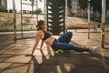 Theme sport and rehabilitation sports medicine. Beautiful strong slender Caucasian woman athlete uses foam roller green field stre Royalty Free Stock Photo