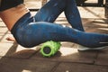 Theme sport and rehabilitation sports medicine. Beautiful strong slender Caucasian woman athlete uses foam roller green field stre Royalty Free Stock Photo