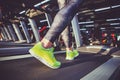 Theme of sport and weight loss. Close-up of the foot of a young strong woman in a light green sneakers on a simulator, running in Royalty Free Stock Photo