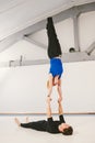 Theme is sports and acreage. A young Caucasian male and female couple practicing acrobatic yoga in a white gym on mats. a man lies Royalty Free Stock Photo