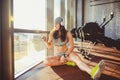 Theme sports, health and technology. beautiful Caucasian woman sportswoman in gray sportswear and hat sits by window with sun