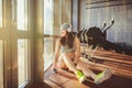 Theme sports, health and technology. beautiful Caucasian woman sportswoman in gray sportswear and hat sits by window with sun