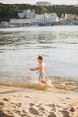 Theme summer outdoor activities near the river on the city beach in Kiev Ukraine. Little funny baby boy running along the river Royalty Free Stock Photo