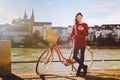 Theme tourism on bicycle and modern technology. Beautiful young caucasian woman stands near red retro bicycle on riverside river R Royalty Free Stock Photo