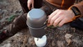 Theme tourism hiking and traveling in nature. Hands Caucasian man uses equipping to cook food outside. tourist places pot of water Royalty Free Stock Photo