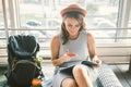 Theme of tourism and travel of young student. Beautiful young caucasian girl in dress and hat sits on floor tourist rug inside Royalty Free Stock Photo