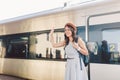 Theme transportation and travel. Portrait of young Caucasian woman with toothy smile standing at train station background with Royalty Free Stock Photo