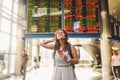 Theme travel and tranosport. Beautiful young caucasian woman in dress and backpack standing inside train station or terminal looki Royalty Free Stock Photo