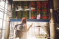 Theme travel and tranosport. Beautiful young caucasian woman in dress and backpack standing inside train station or terminal looki Royalty Free Stock Photo