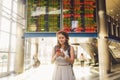 Theme travel and tranosport. Beautiful young caucasian woman in dress and backpack standing inside train station or terminal looki Royalty Free Stock Photo