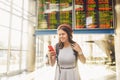 Theme travel and tranosport. Beautiful young caucasian woman in dress and backpack standing inside train station or terminal looki Royalty Free Stock Photo