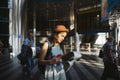 Theme travel and transportation. Beautiful young caucasian woman in dress and backpack standing inside train station terminal