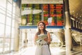 Theme travel and transportation. Beautiful young caucasian woman in dress and backpack standing inside train station terminal