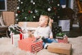 Theme winter and Christmas holidays. Child boy Caucasian blond 1 year old sitting home floor near Christmas tree with New Year dec