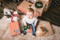 Theme winter and Christmas holidays. Child boy Caucasian blond 1 year old sitting home floor near Christmas tree with New Year dec