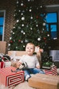 Theme winter and Christmas holidays. Child boy Caucasian blond 1 year old sitting home floor near Christmas tree with New Year dec