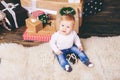 Theme winter and Christmas holidays. Child boy Caucasian blond 1 year old sitting home floor near Christmas tree with New Year dec