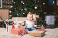 Theme winter and Christmas holidays. Child boy Caucasian blond 1 year old sitting home floor near Christmas tree with New Year dec