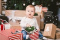 Theme winter and Christmas holidays. Child boy Caucasian blond 1 year old sitting home floor near Christmas tree with New Year dec