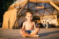 Theme is yoga and children. Caucasian Boy child sitting barefoot cross-legged in lotus position on wooden floor the Royalty Free Stock Photo