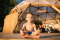 Theme is yoga and children. Caucasian Boy child sitting barefoot cross-legged in lotus position on wooden floor the Royalty Free Stock Photo