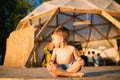 Theme is yoga and children. Caucasian Boy child sitting barefoot cross-legged in lotus position on wooden floor the Royalty Free Stock Photo