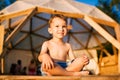 Theme is yoga and children. Caucasian Boy child sitting barefoot cross-legged in lotus position on wooden floor the Royalty Free Stock Photo