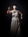 Themis, goddess of justice blindfolded, with scales and a sword in her hands.