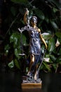 Themis statue, concept of law and justice on the background of a green flowerpot Royalty Free Stock Photo