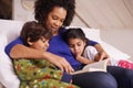 And then they lived happily ever after...A young mother reading to her children while relaxing at home. Royalty Free Stock Photo