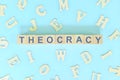 Theocracy government form concept. Wooden blocks typography flat lay in blue background. Royalty Free Stock Photo